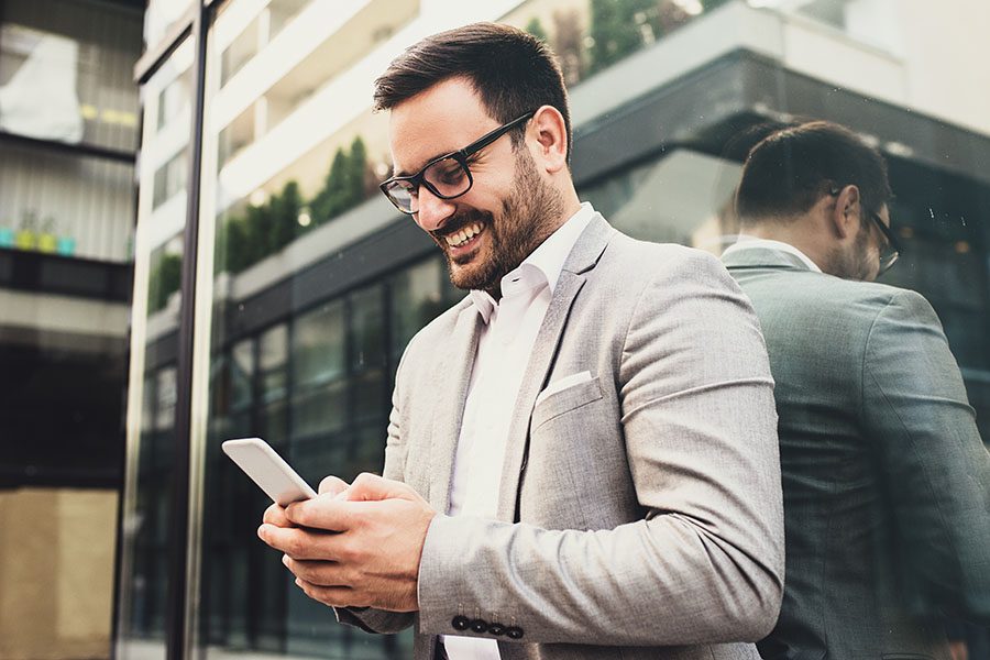 Client Center - Businessman Standing Outside Modern Office Building Using Phone