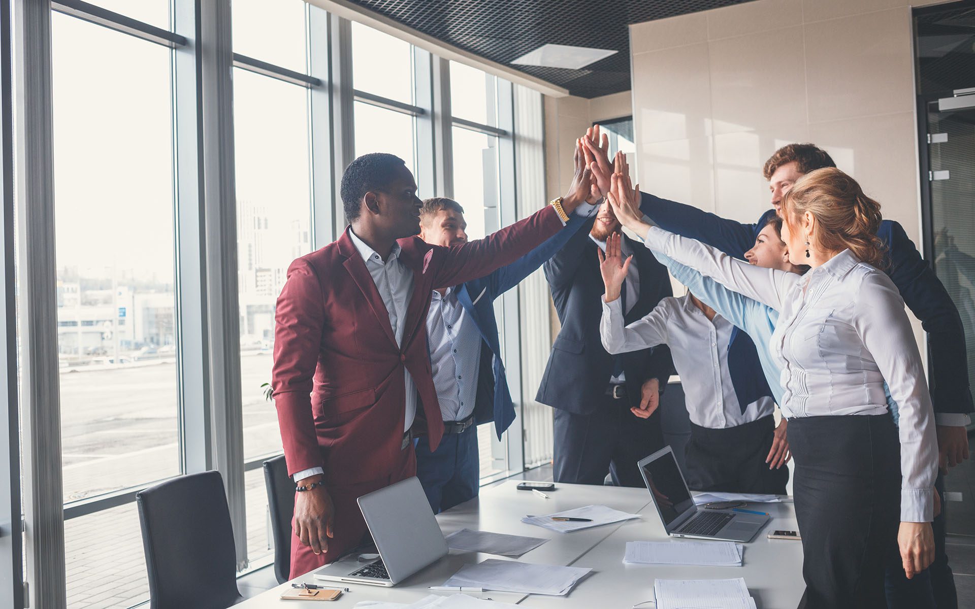 Homepage - Group Of Employees At Office Giving Eachother High Fives